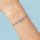Bracelet with pink beads and a bow on a wrist against a light blue background